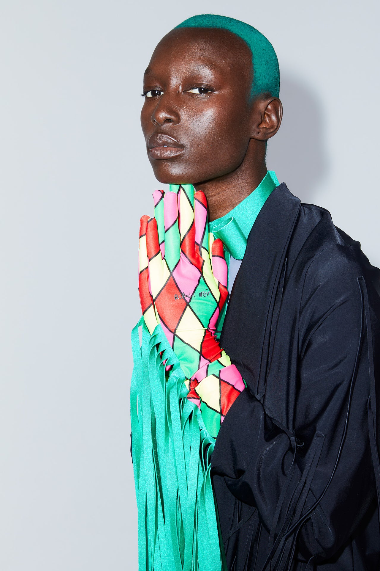 Ruban Noir fringe gloves in red, pink, green and yellow diamond print outlined in black. Green long fringe. Shown on model in black fringe jacket and green bowtie choker.