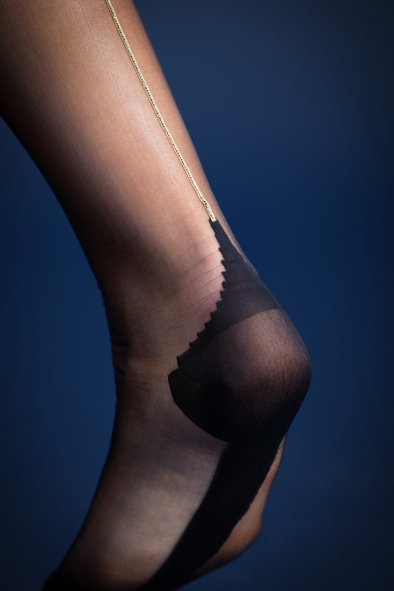 Vixen & Fox Deco gold lurex seamed stockings in black. Close up back view of suspender attached to the welt of the stocking.