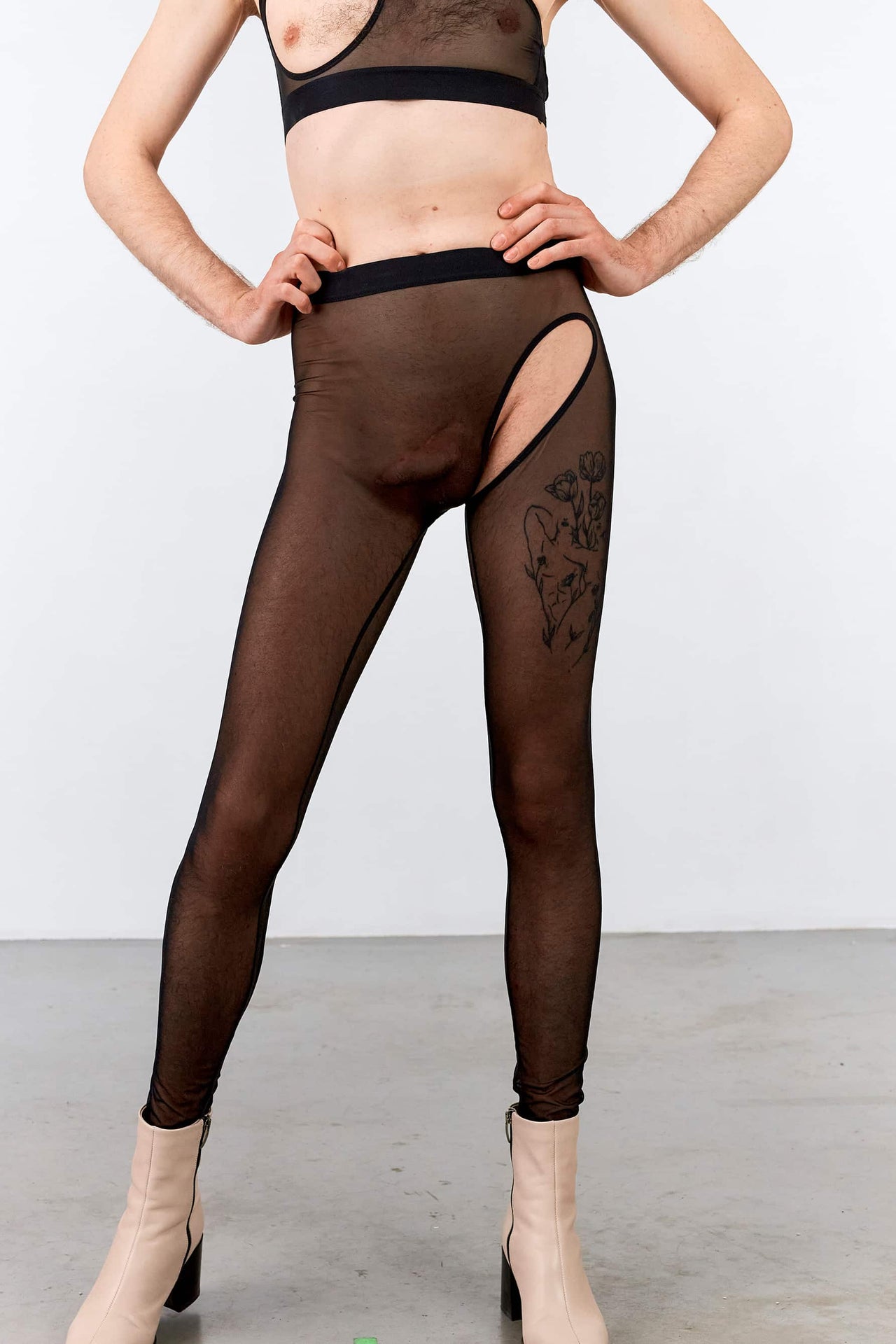 La Fille d'O In Furs unisex black mesh leggings, front view on model. Image shows cutout on front left and sheer silhouette with prominent inner leg seams and wide elastic waistband.