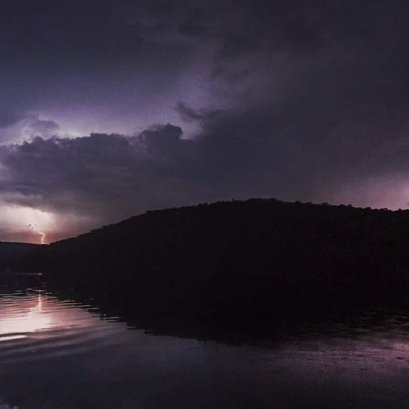 Lightning over a hill and lake at night