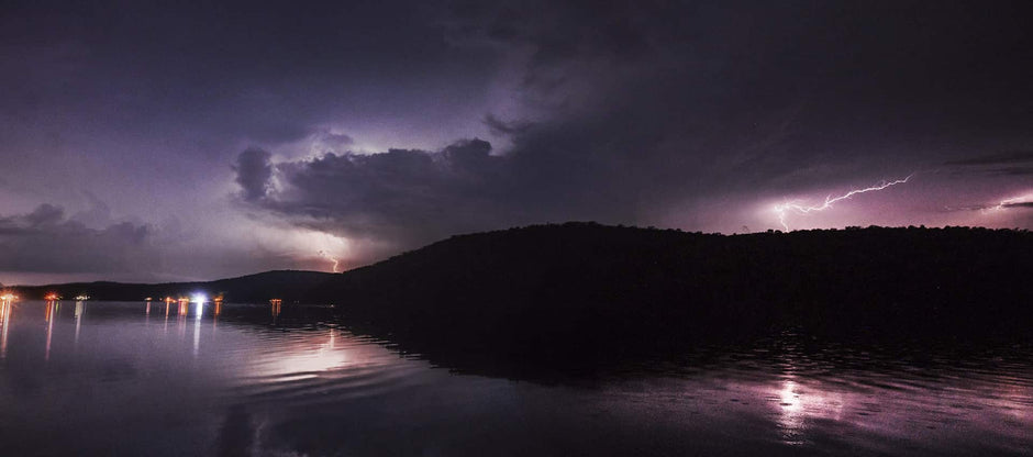 Lightning over a hill and lake at night