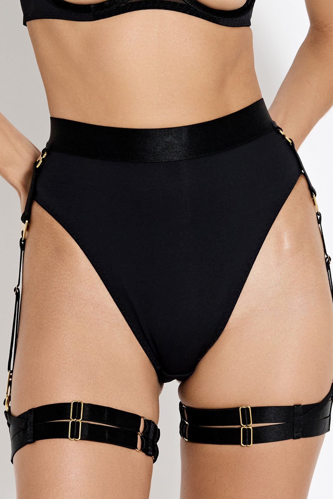 Bordelle Syra high waist high leg thong with suspenders and garters in black, front view on model.