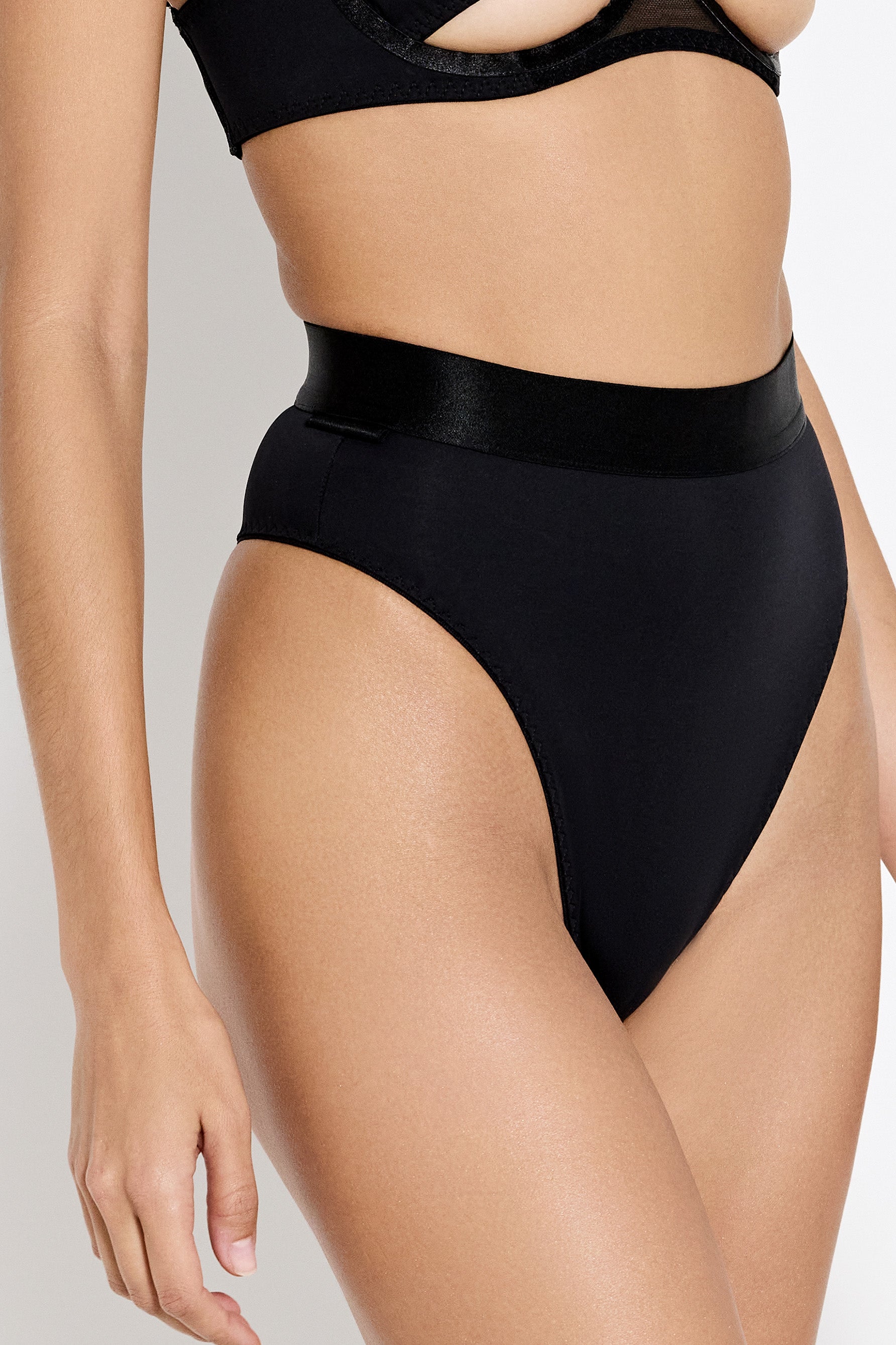 Bordelle Syra high waist high leg thong in black, with wide elastic waistband, side view on model.