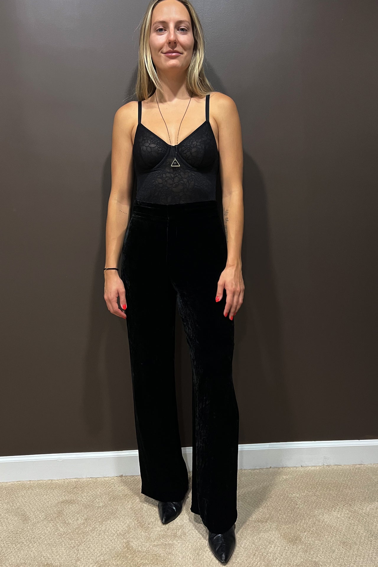 Else Eden floral mesh underwire bodysuit in black. Front view on model shown wearing with high waist velvet trousers and pointy boots. Image shows the thin elastic shoulder straps and semi-sheer design. 