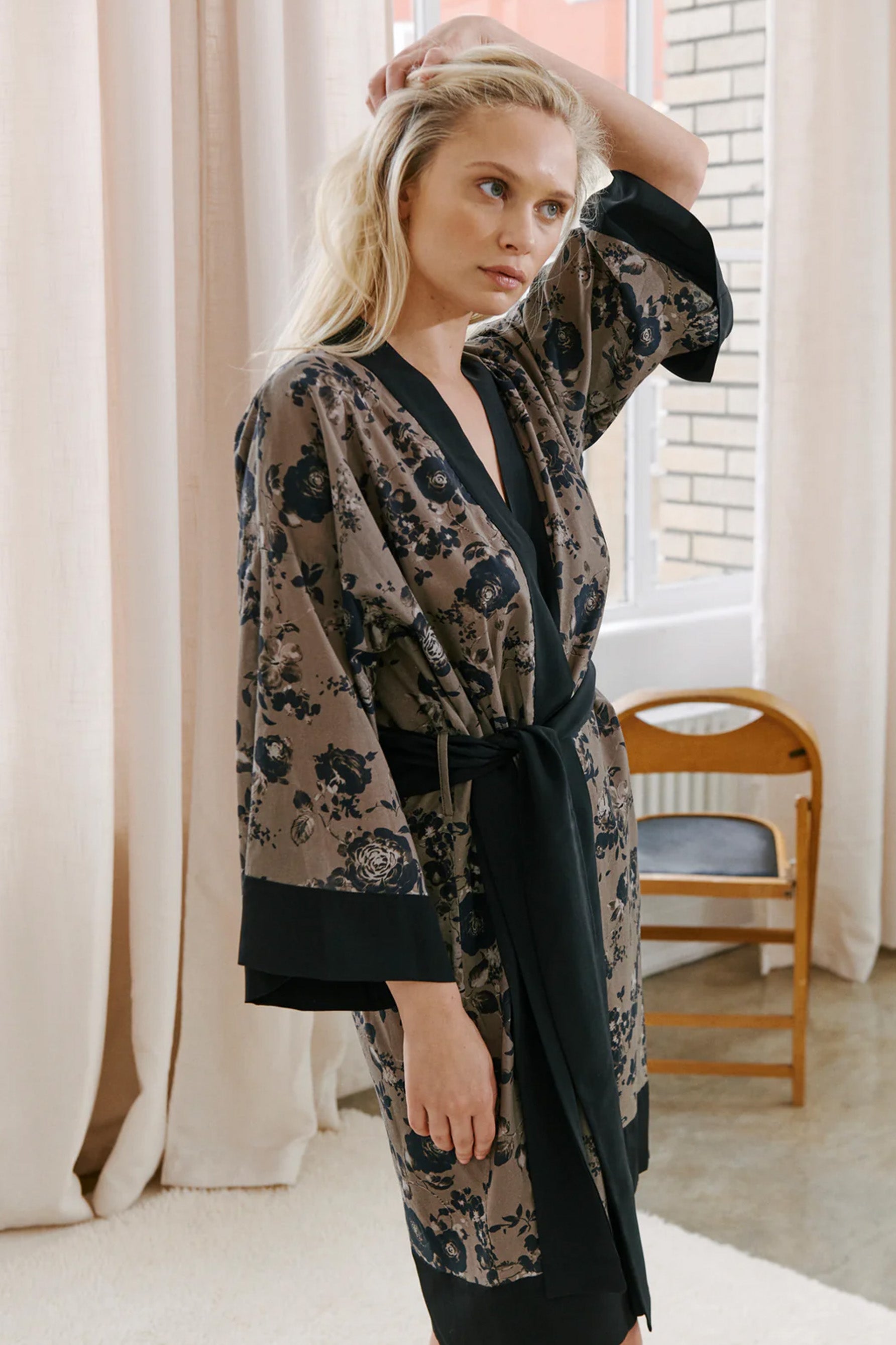 Else Euphoria taupe robe with black floral print and black silk trim. Image shows the robe on model, front view, featuring the wide kimono style sleeves, knee length him and silk waist tie.