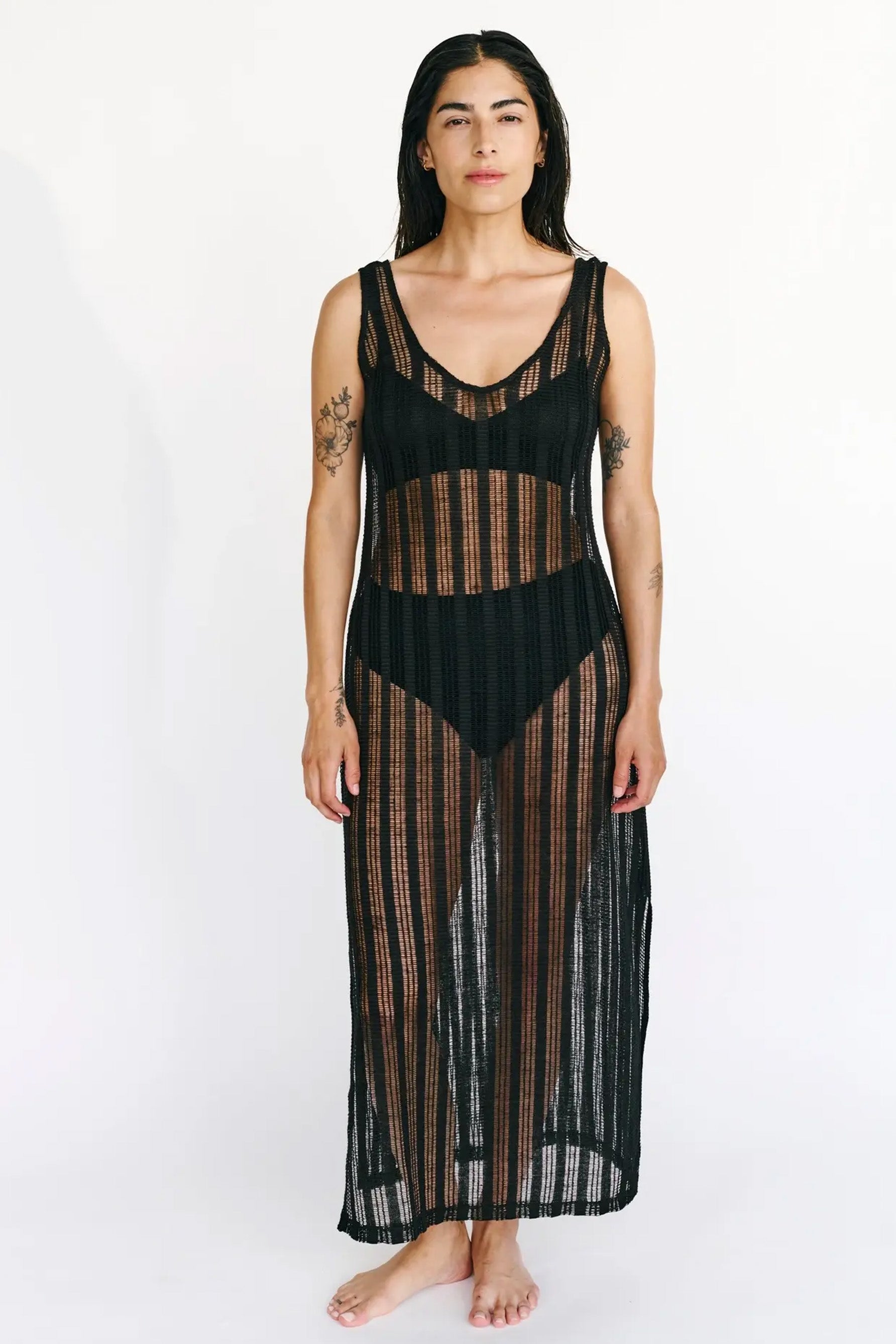 Else St. Tropez black knit swim coverup dress. The knit features a sheer striped pattern. The sleeveless dress has a scoop neck and side slits, with an ankle length hemline. Front view shown on model wearing a two piece black swimsuit underneath.