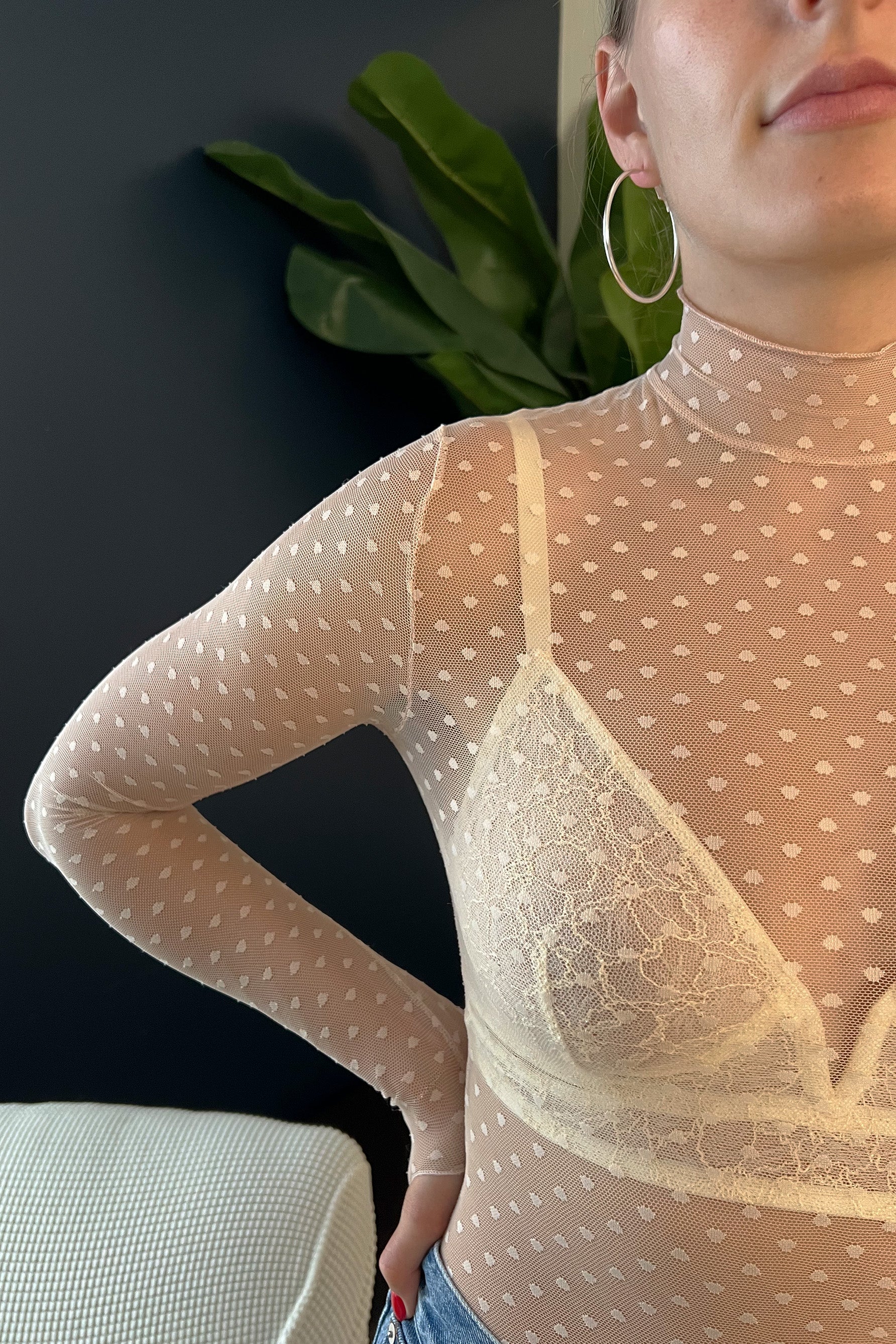 Close up of Only Hearts Coucou Lola long sleeve turtle neck bodysuit. Image shows ivory lace bralette underneath and sheer polka dot mesh of bodysuit. 