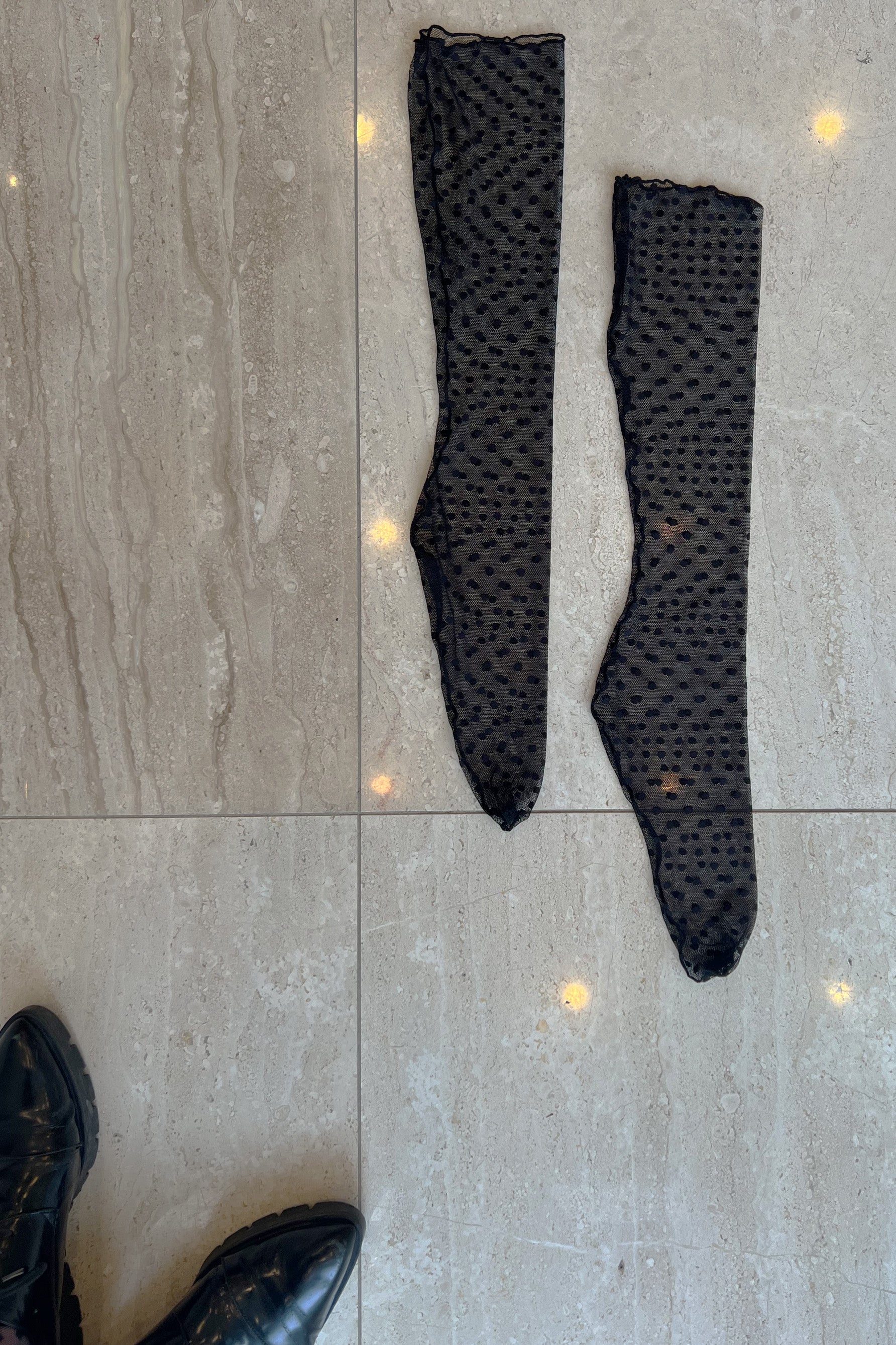 Only Hearts Coucou Lola sheer polka dot mesh ankle socks in black. Shown flat on marble floor. Image shows rolled edge top, back seam, and sheer design. 