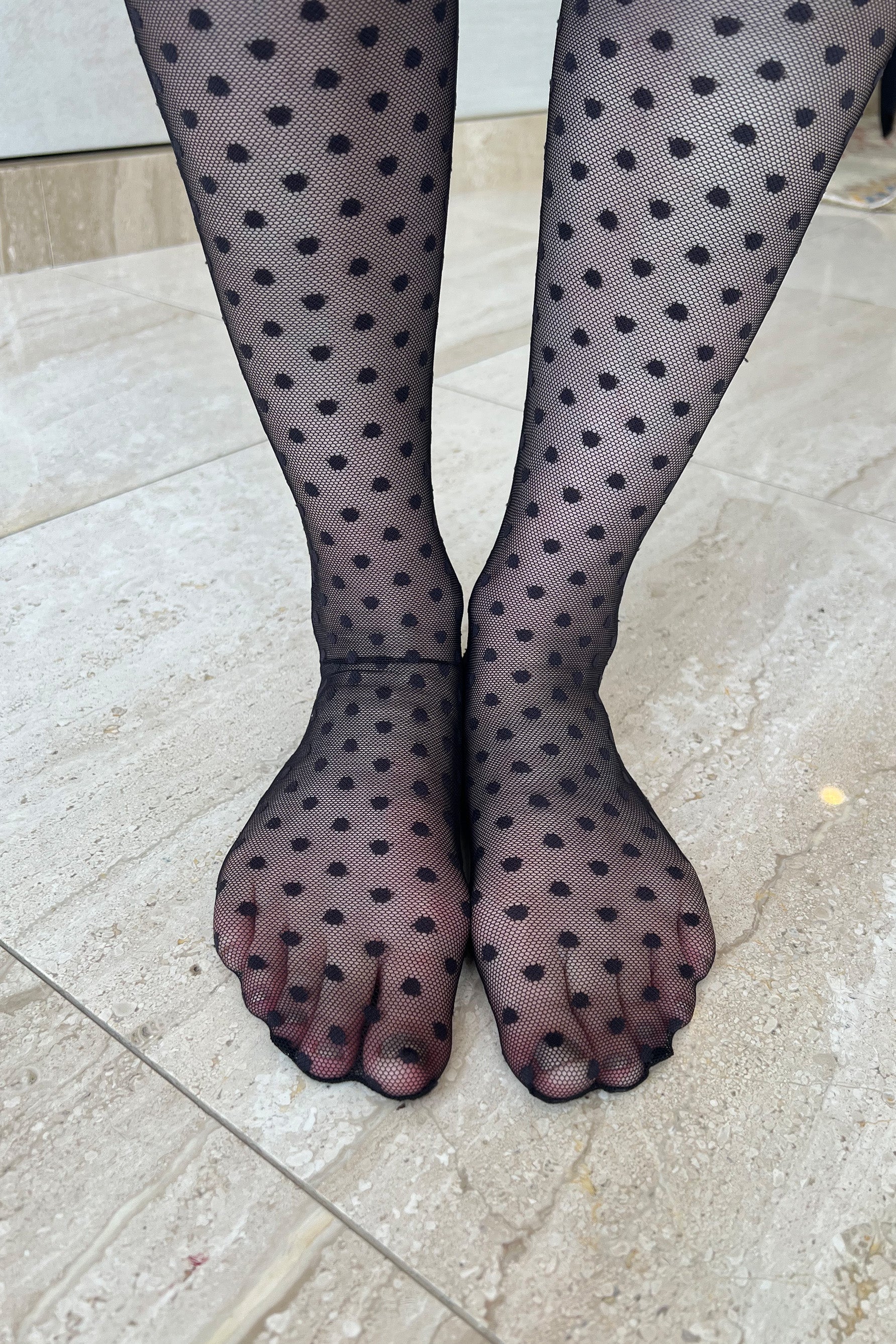 Only Hearts Coucou Lola ankle socks in black, front view on model. Image shows socks pulled up near the knee, polka dot mesh, and rolled edge top. Model wears no shoes so fully sheer foot is shown.