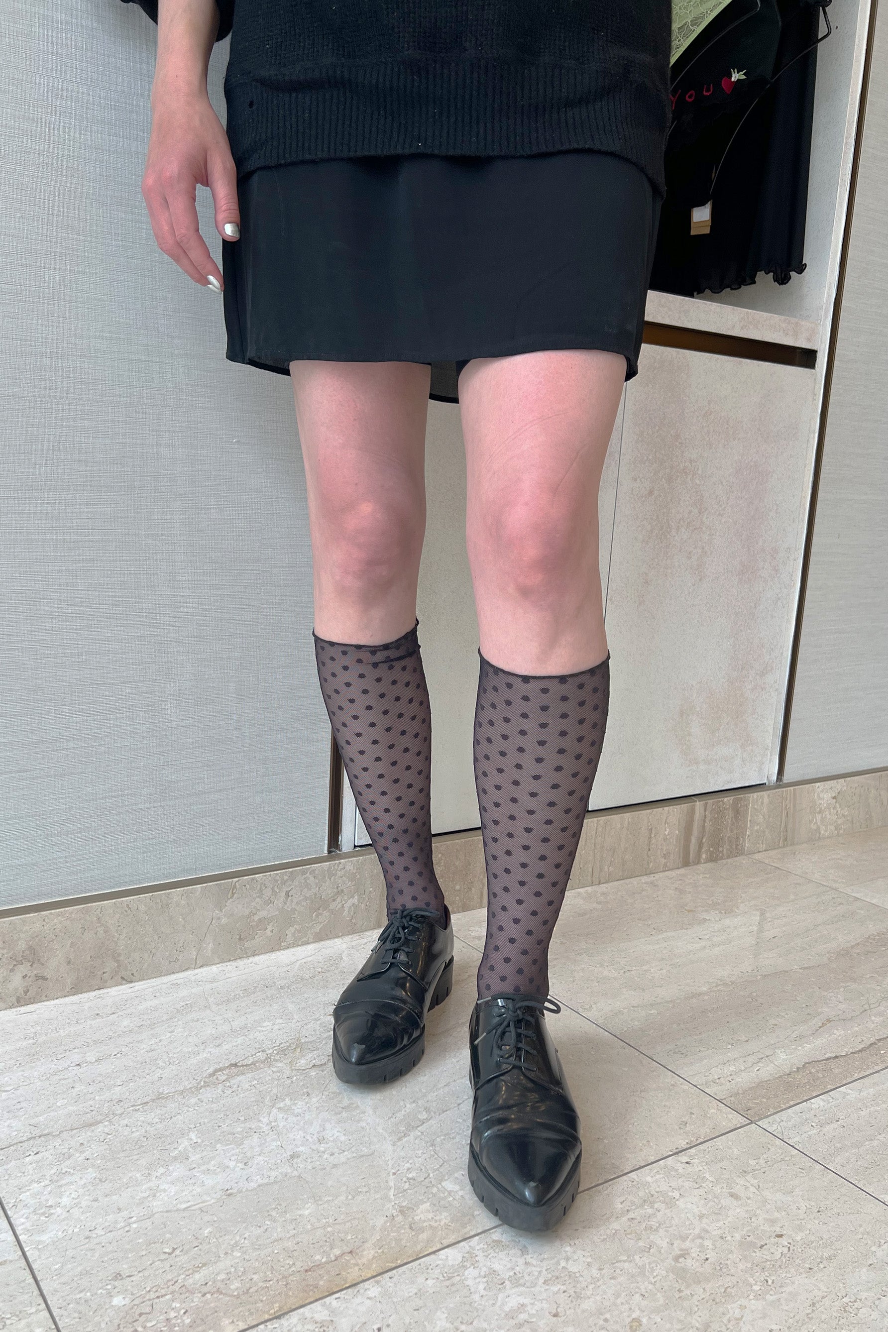 Only Hearts Coucou Lola ankle socks in black, front view on model. Image shows socks pulled up near the knee, polka dot mesh, and rolled edge top. Shown styled with pointy creeper style shoe and mini skirt. 