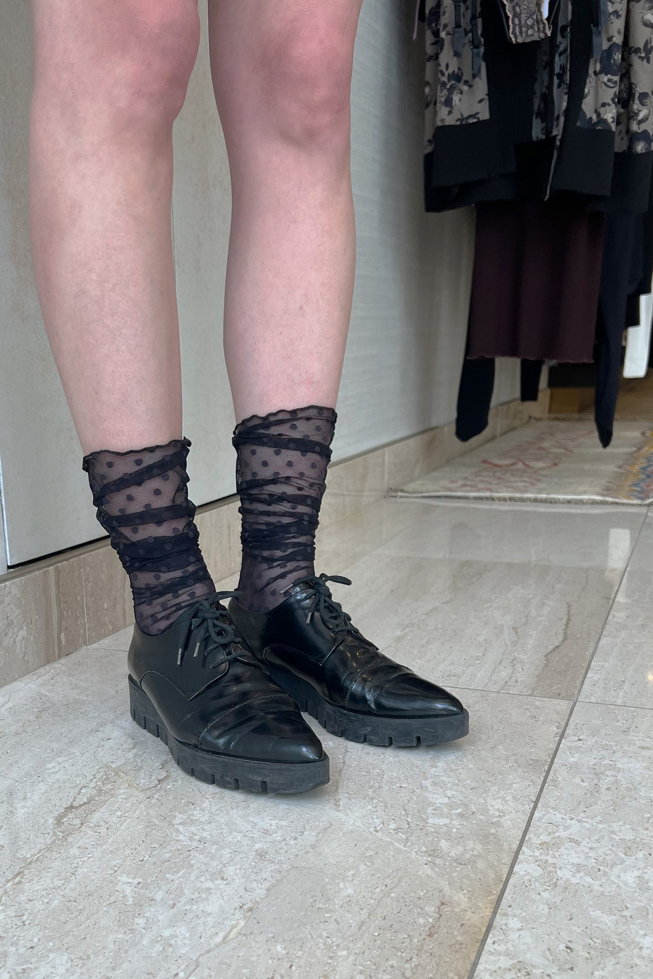 Only Hearts Coucou Lola ankle socks in black, front view on model. Image shows socks pulled up near the knee, polka dot mesh, and rolled edge top. Shown styled with pointy creeper style shoe and mini skirt. 