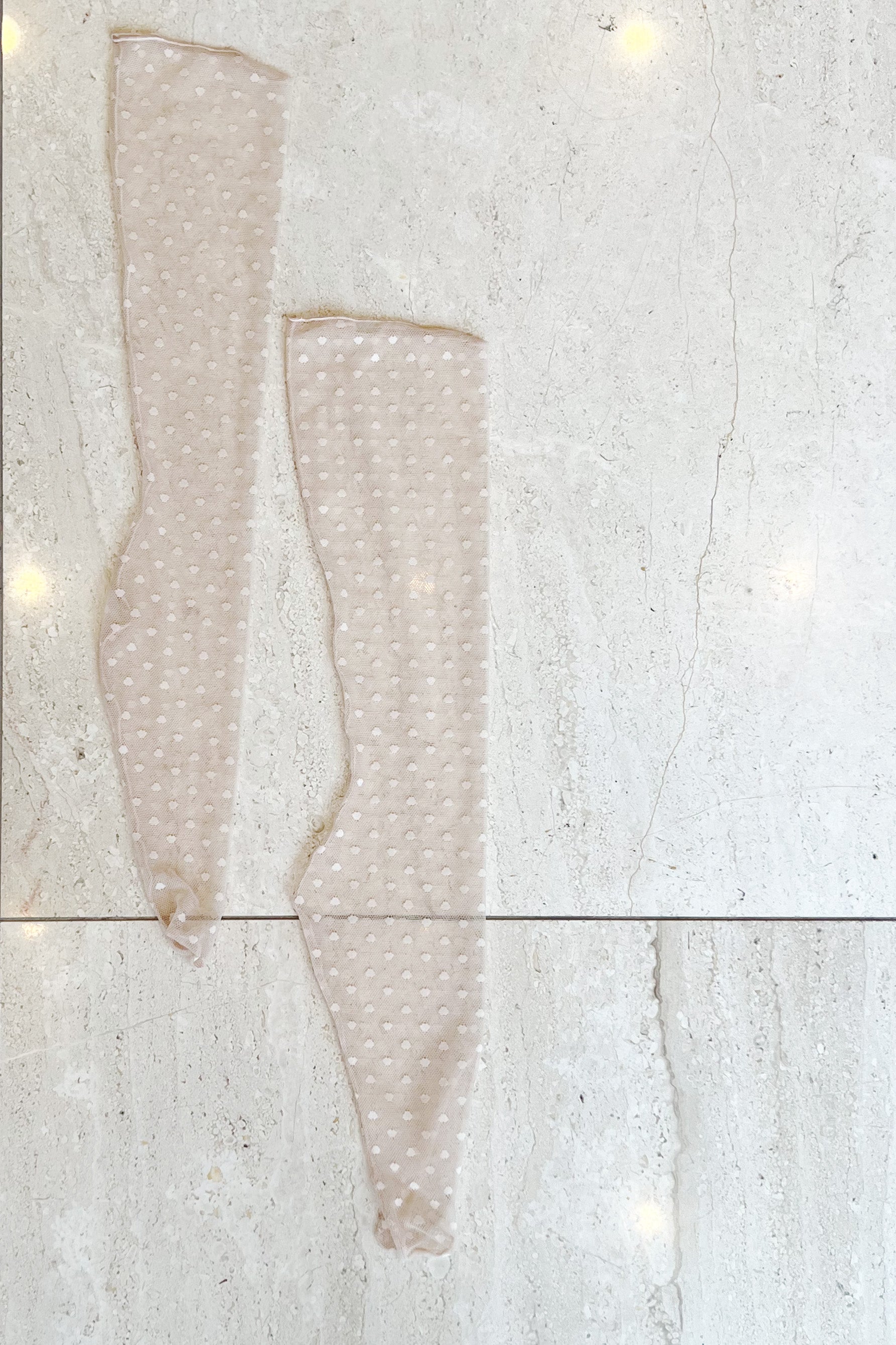 Only Hearts Coucou Lola ankle socks in light pink/beige tinted. Shown flat on marble floor. Image shows the back seam, rolled edge top, and polka dot mesh. 