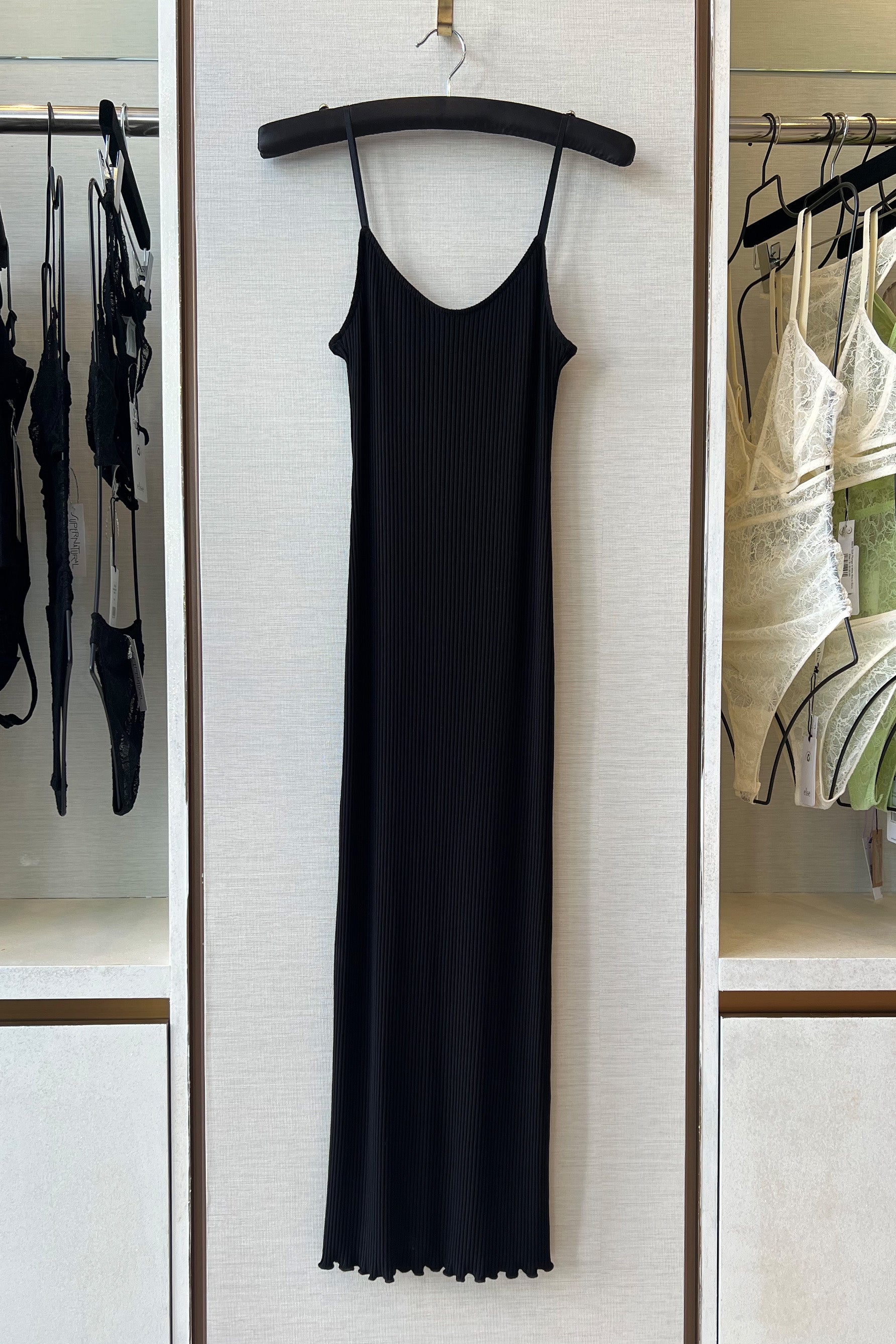 Only Hearts Eco Rib slip dress in black, front view on hanger. Image shows the scoop neckline, ribbed knit, spaghetti straps, and lettuce edge hemline.