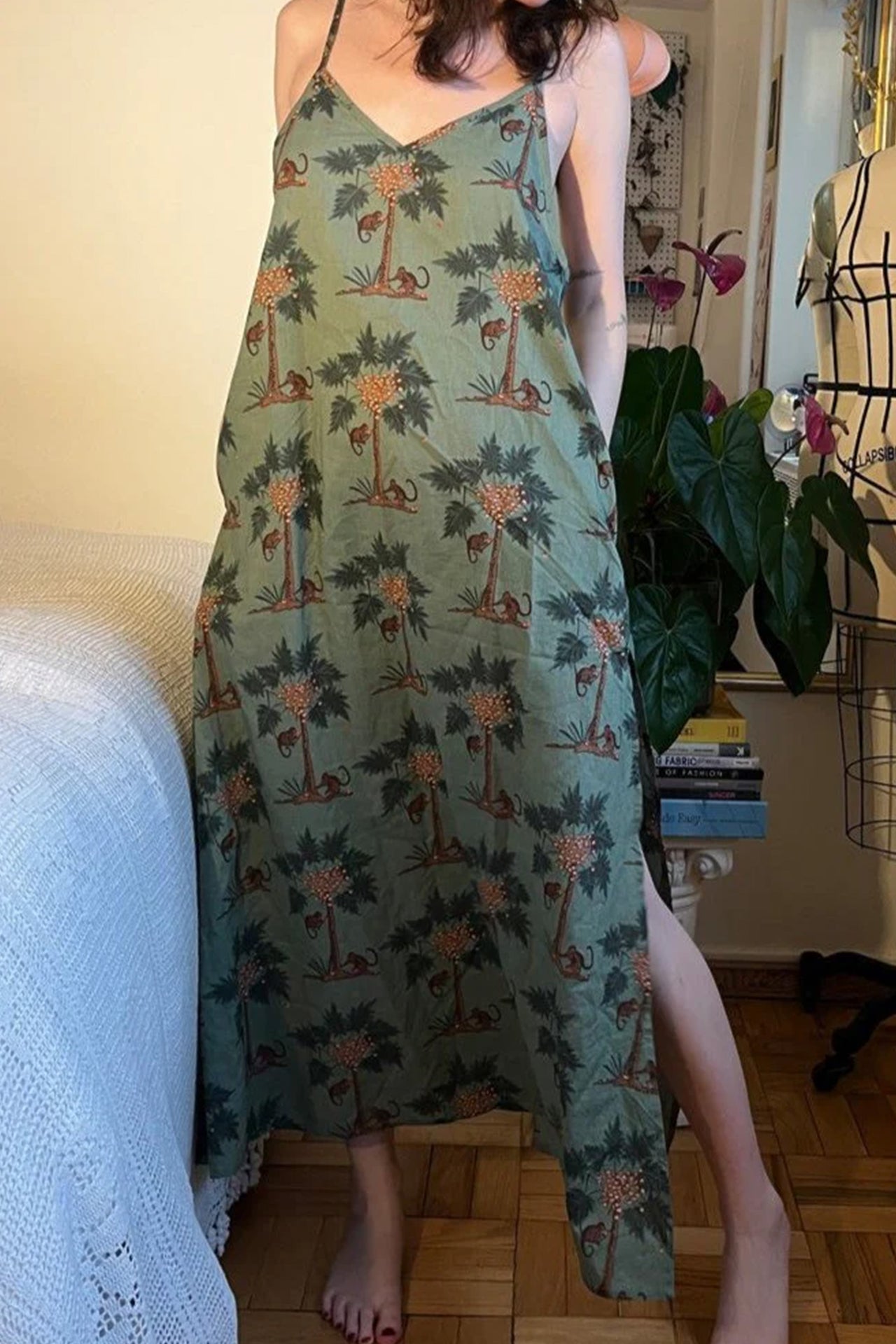 Only Hearts Luv Island cotton night dress, back view on model. Image shows adjustable spaghetti straps, pockets, and side slits. Nightgown is muted green with palm tree and monkey print. 