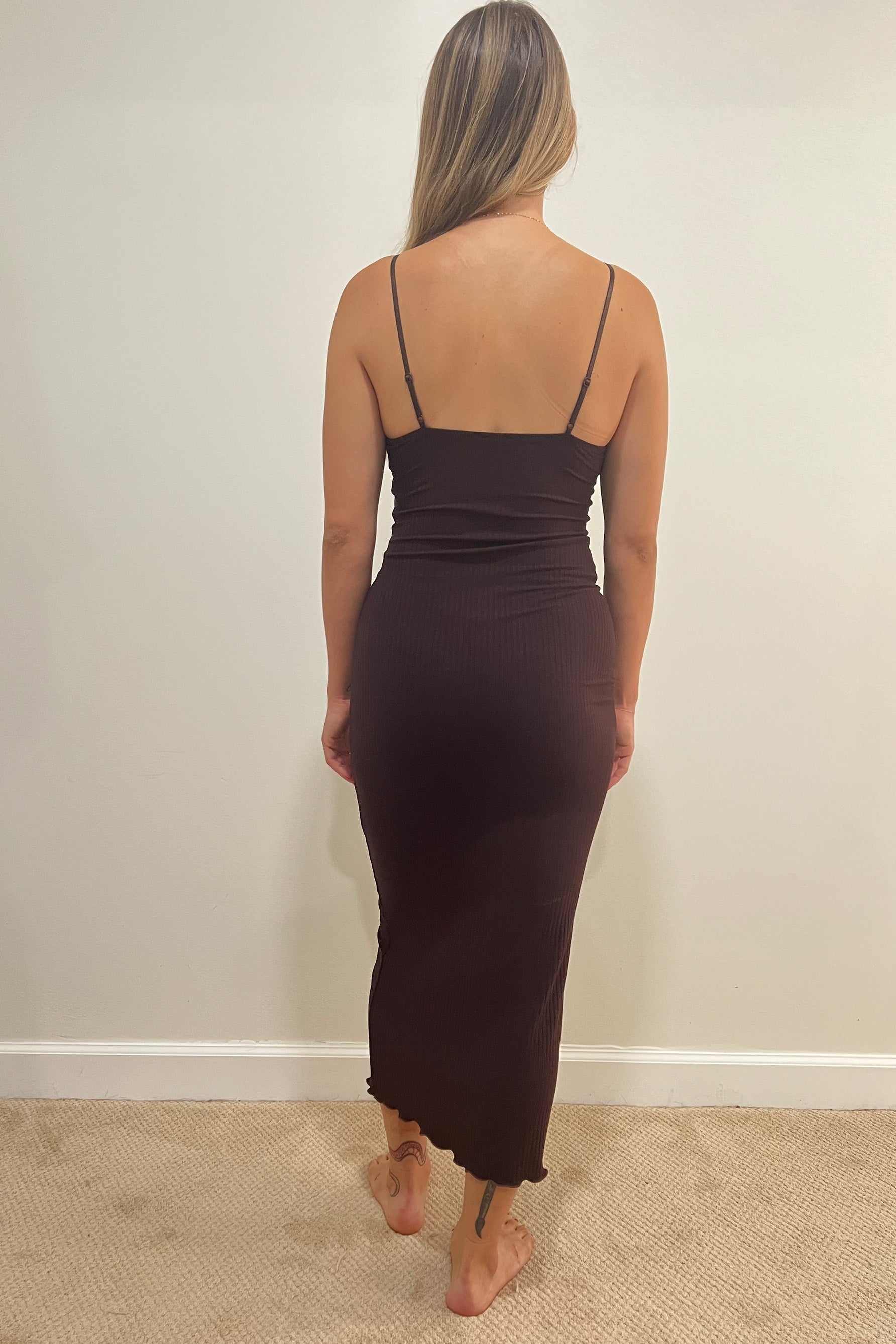 Only Hearts Eco Rib slip dress in dark brown caffeine, back view on model. Image shows adjustable spaghetti straps, straight back, fitted silhouette, ribbed knit, and lettuce edge midi/maxi hemline. 