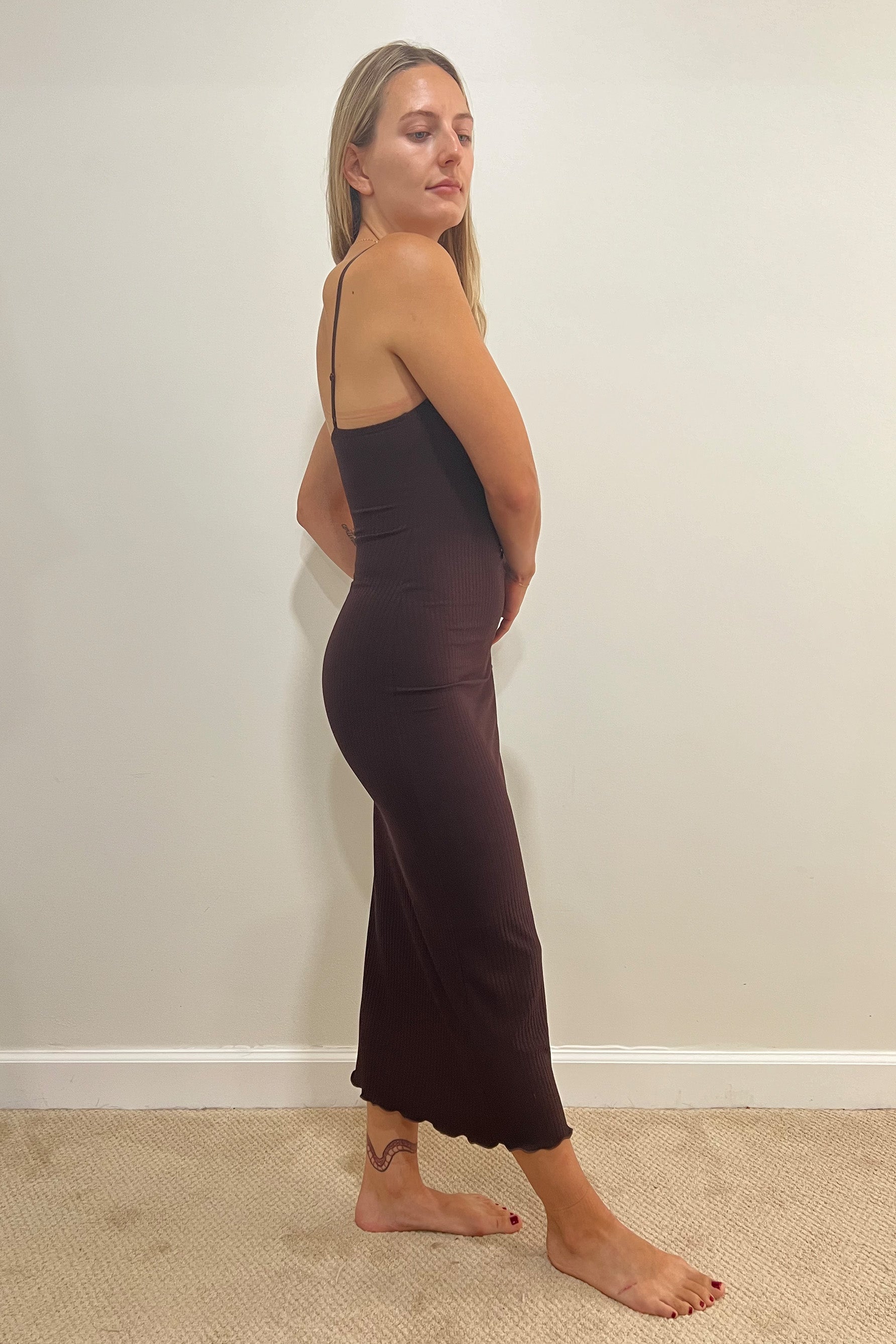 Only Hearts Eco Rib slip dress in dark brown caffeine, side view on model. Image shows spaghetti straps, fitted silhouette, ribbed knit, and lettuce edge midi/maxi hemline. 