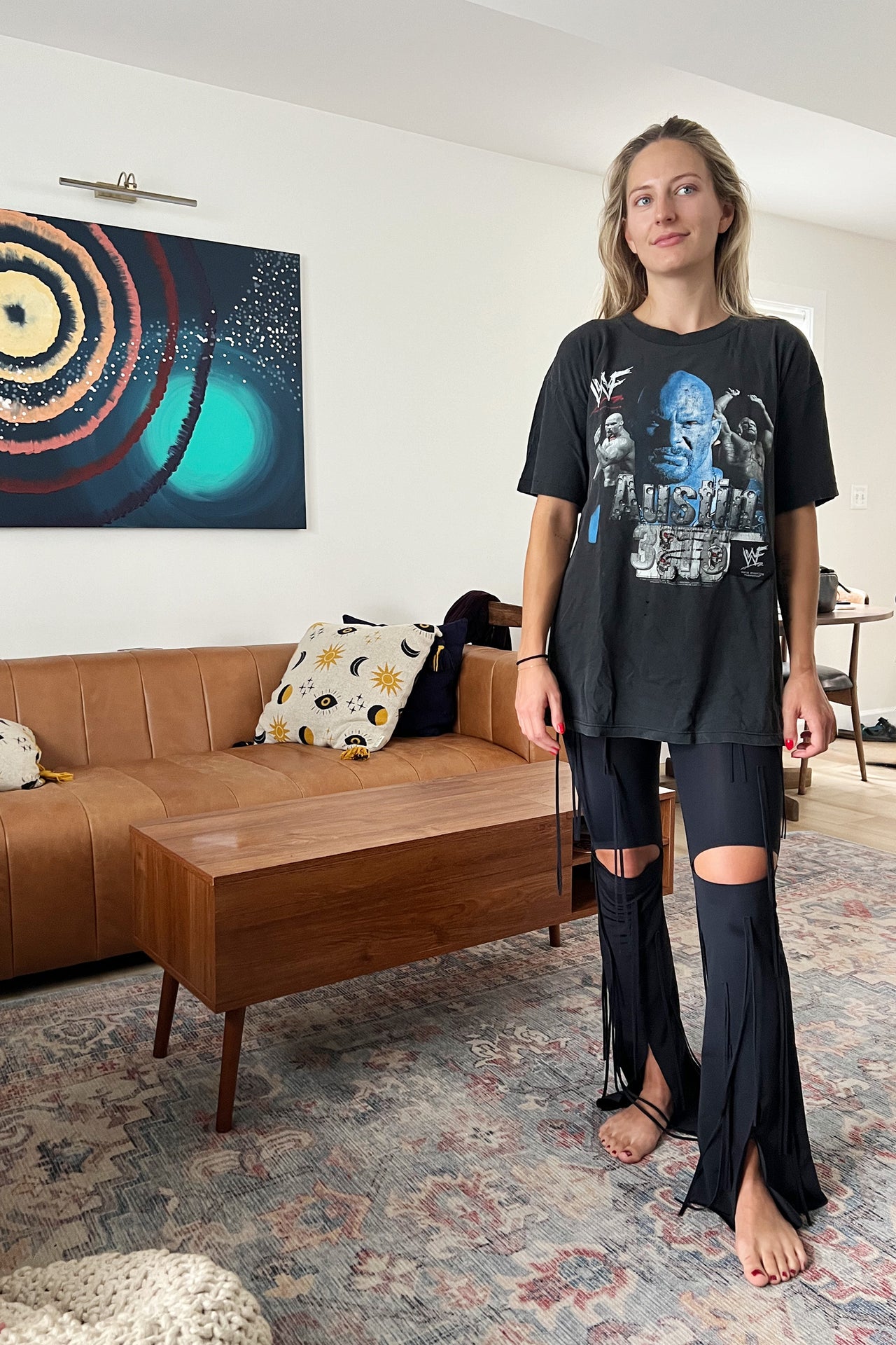 Ruban Noir black fringe cutout pants, front view on model in oversized t-shirt. Image shows the above knee cutouts, flared leg, and front slit at leg, and long fringes throughout. 