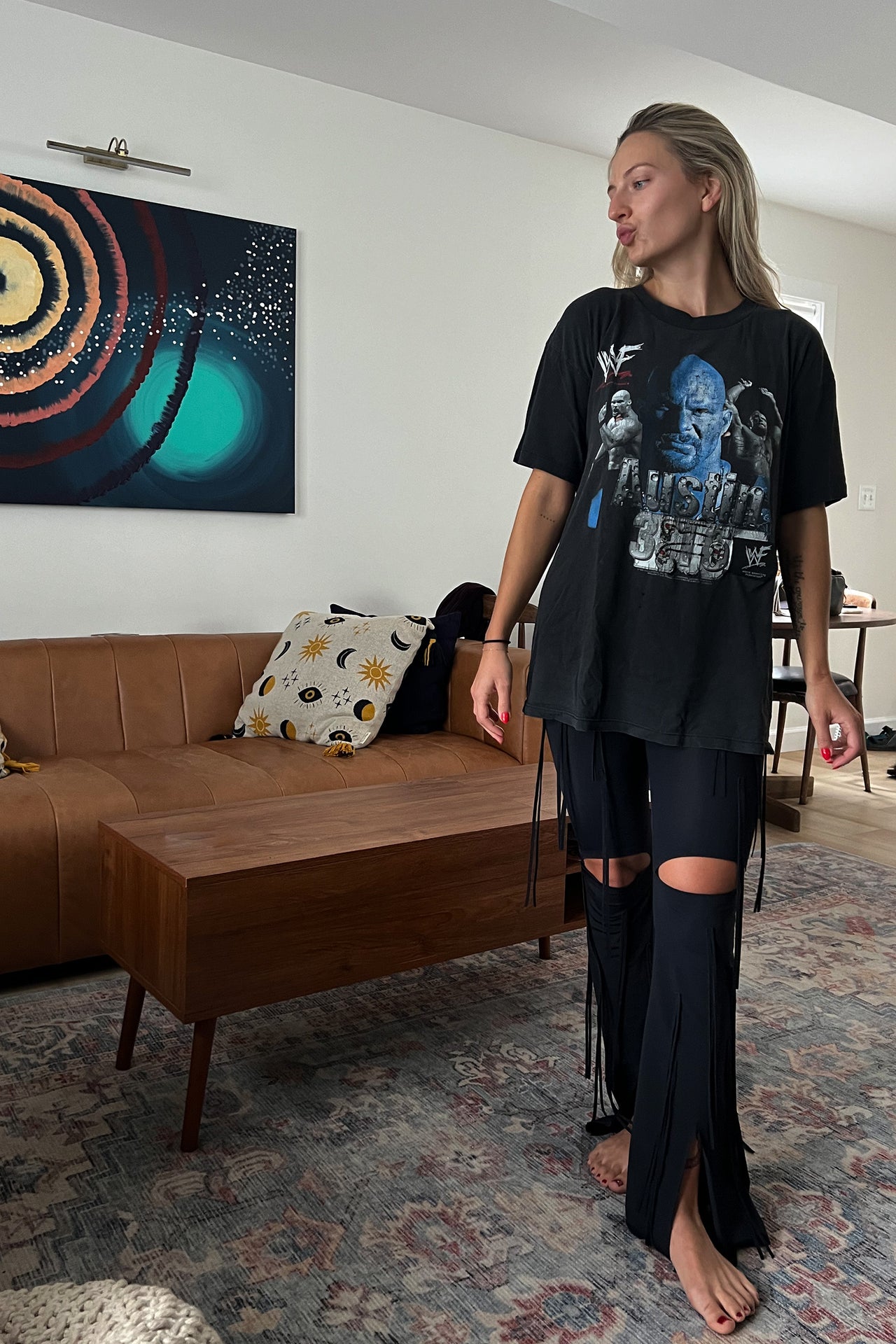 Ruban Noir black fringe cutout pants, front view on model in oversized t-shirt. Image shows the above knee cutouts, flared leg, and front slit at leg, and long fringes throughout. 