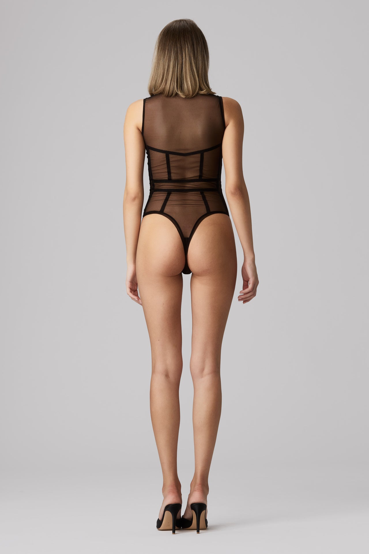 Murmur Cage black sheer mesh bodysuit with graphic black trim around bust, waist, and vertically on torso. High cut neck and legs, sleeveless design. Front view on model.