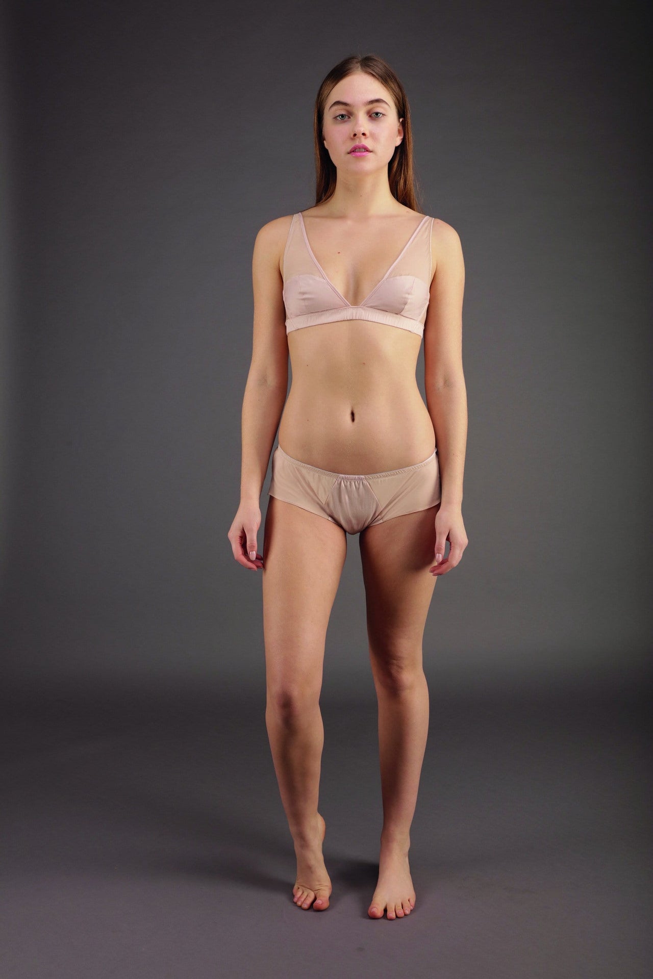 Rossell England Crescent bra in blush pink, front view on model in matching boyshorts. Triangle high apex cups, lower part is opaque cotton with upper part sheer silk. Cotton underband.