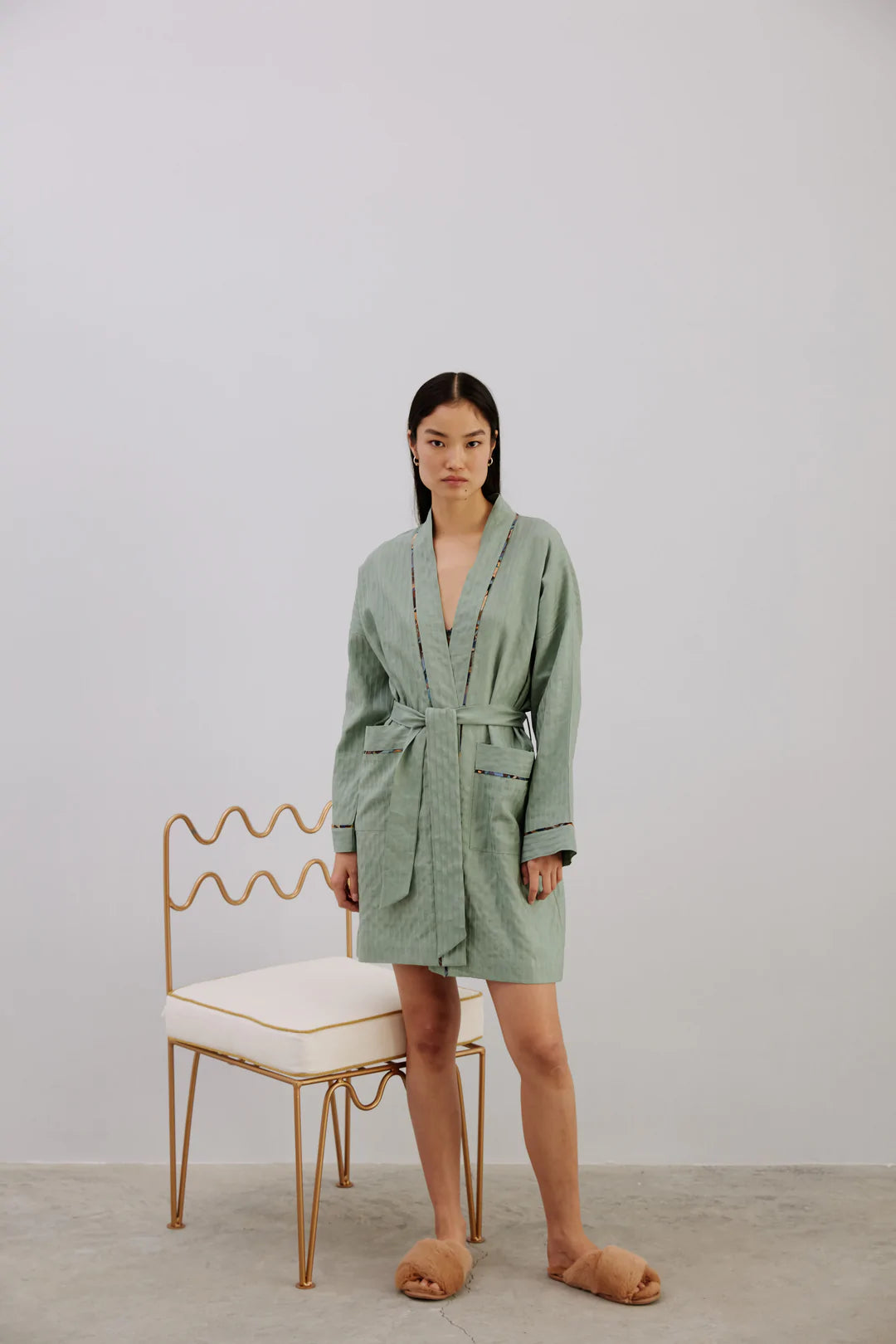 Else Constantinople light green robe, shown on model, front view. Robe has an above the knee hemline and a striped texture weave, with silk trim on the collar, front pockets and sleeve cuffs. Shown closed with waist tie.