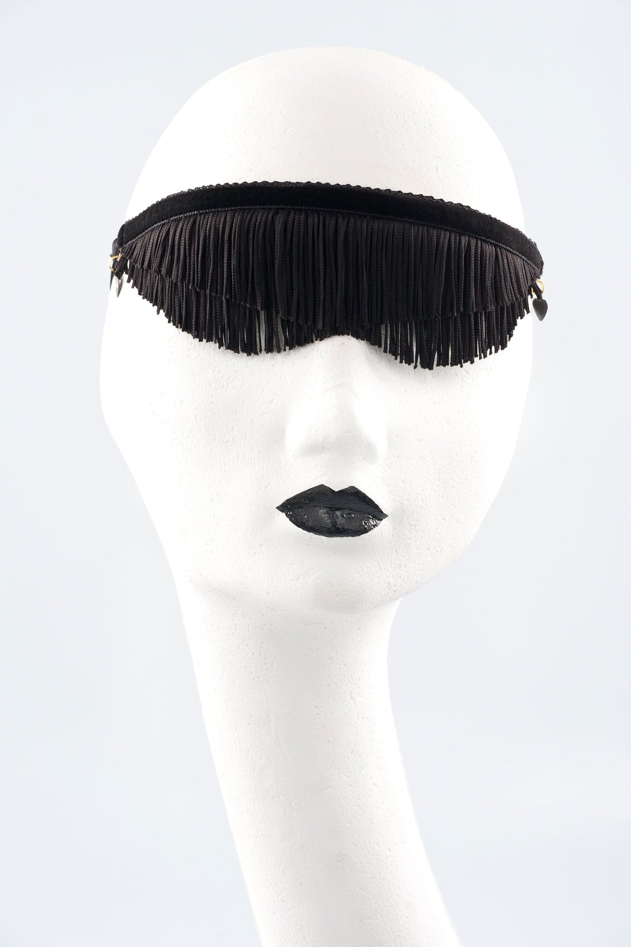 Fraulein Kink Justine black fringe blindfold, front view on model. Two layers of fringe bound by velvet band. Curved hem like sunglasses under eyes. Second model in red version also pictured. 