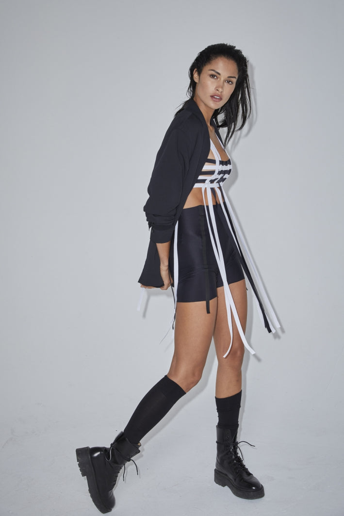 Ruban Noir black and white fringe bra top, shown on model, front view, with matching black blazer and bike shorts, and black knee socks and combat boots